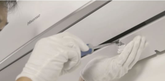 Technician removing the bottom panel of an indoor unit to facilitate access to the pipes